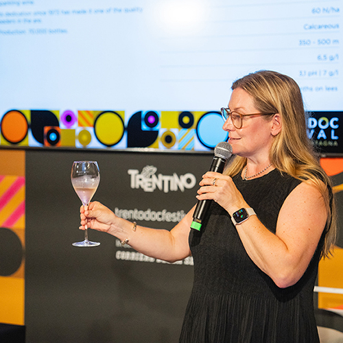 Un Wine Talk del Trentodoc Festival, relatrice con calice in mano davanti al logo dell'evento